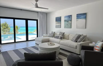 Living room with white sofa and ocean view at Beyond Blue Exuma, Moss Town, Great Exuma